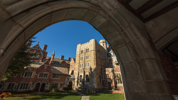 sun shining on part of the Law School as seen through a stone arch
