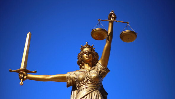 bronze statue of lady justice against a blue sky