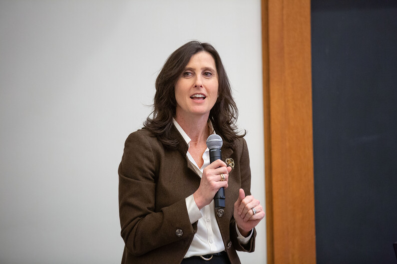 Professor Abbe Gluck speaking holding a microphone