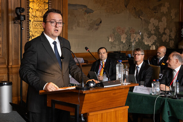 Anton Korynevych speaking at a podium in an ornate room at a hearing