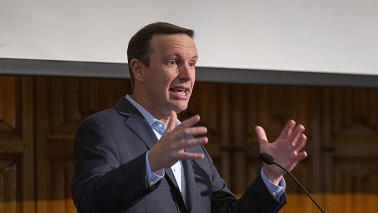 Senator Chris Murphy speaking at podium with hands raised