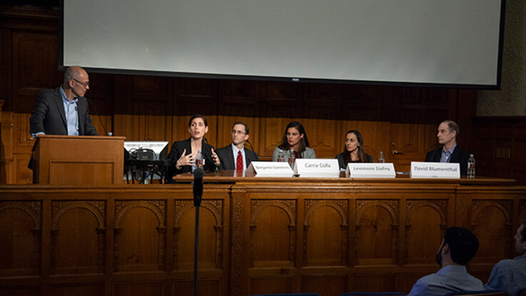 Panel 3 seated at desk at front of lecture hall