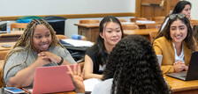 three students smiling at a desk in a YLS classroom