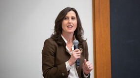 Professor Abbe Gluck speaking holding a microphone
