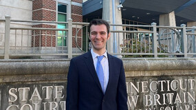 Ryan Sandler wearing a dark suit and blue tie in front of Connecticut Superior Court