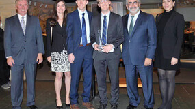 A group of six people standing for a photo with one holding an award
