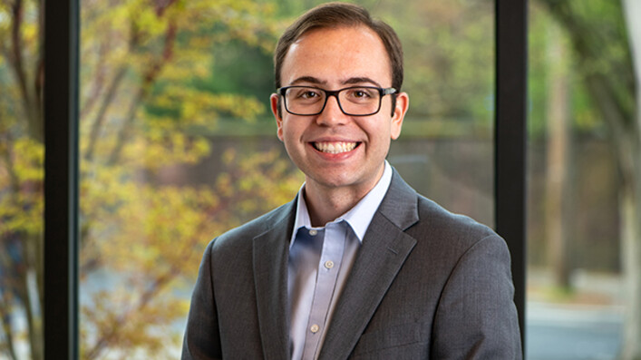 Christopher D’Urso ’24 in front of a window with trees behind